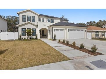 Beautiful two-story home featuring an attached three-car garage and a well-manicured lawn at 1703 Cedar St, Safety Harbor, FL 34695