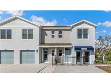 A two story townhome featuring neutral paint, garage, and covered entryway with decorative metal fencing at 4596 Stargazer Ct, Palm Harbor, FL 34683