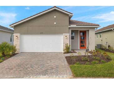 Modern one-story home with a two-car garage and landscaped front yard at 12236 Meditation Trl, Venice, FL 34293