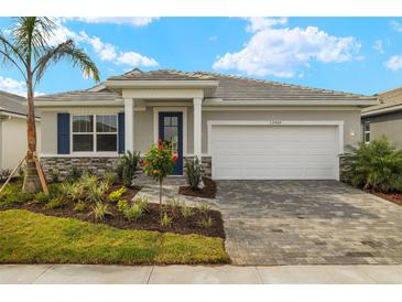 Charming single-story home showcasing a landscaped front yard, stone accents, and a two-car garage at 17909 Solstice Ave, Venice, FL 34293