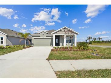 Inviting single-story home with a well-maintained lawn, gray paint, and an attached two-car garage at 11826 Richmond Trl, Parrish, FL 34219