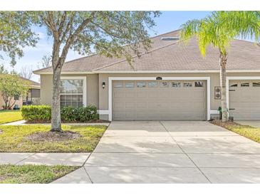 Tan house with a two-car garage and well-manicured lawn at 4427 Ashton Meadows Way, Wesley Chapel, FL 33543