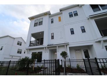 Three-story townhome with white siding, black windows, and a small front yard at 7244 Sutton Ln, Sarasota, FL 34240