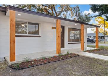 Modern white house with wood columns, landscaping, and walkway at 1920 E Shadowlawn Ave, Tampa, FL 33610