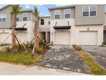 Modern townhome with gray exterior, two-car garage, and landscaped front yard at 31471 Woodland Race Loop, Wesley Chapel, FL 33545