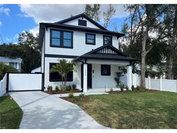 Striking two-story home features black trim, crisp white facade, manicured lawn, and a modern driveway at 4204 N 13Th St, Tampa, FL 33603