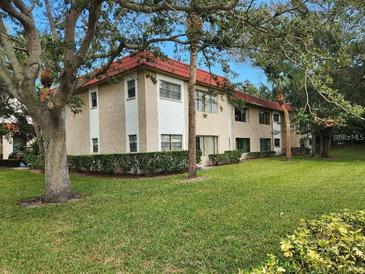 Exterior view of condo building with lush landscaping and a well-maintained lawn at 1753 Belleair Forest Dr # F3, Belleair, FL 33756