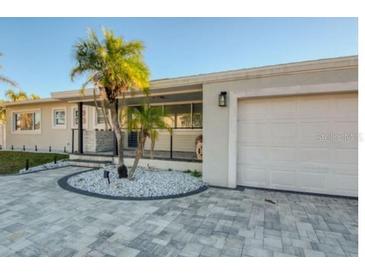 Updated home exterior boasts a modern design, paver driveway, and landscaped entry at 1866 Venetian Point Dr, Clearwater, FL 33755