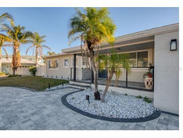 This updated home features a modern exterior, paver driveway, and nicely landscaped entry at 1866 Venetian Point Dr, Clearwater, FL 33755