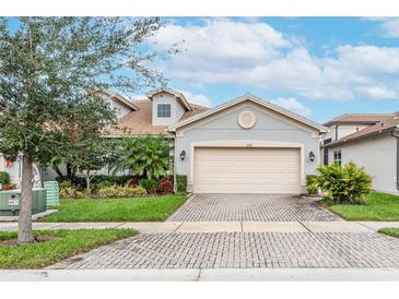 Two-story house with gray siding, a large garage, and a brick paved driveway at 4735 Avila Lakes Dr, Wimauma, FL 33598