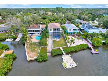 Aerial view of waterfront home with private dock and lush landscaping at 7145 Peninsular Dr, New Port Richey, FL 34652