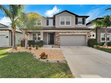 Two-story house with gray siding, stone accents, and a landscaped lawn at 11411 Alachua Creek Ln, Riverview, FL 33579