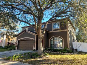 Two-story house with brown exterior, large tree, and attached garage at 12705 Longcrest Dr, Riverview, FL 33579