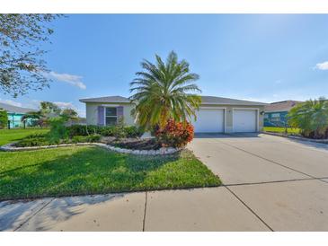 Charming single-story home boasts a two-car garage, landscaped front yard with a palm tree, and a concrete driveway at 5440 Sandy Shell Dr, Apollo Beach, FL 33572