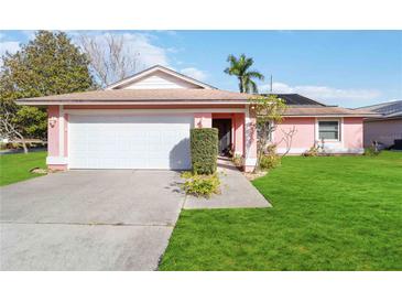 Pink house with a white garage door and a well-maintained lawn at 7853 Sundown Dr, St Petersburg, FL 33709