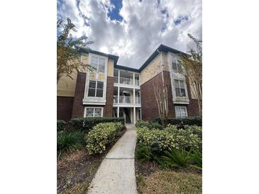 Two-story condo building with brick and siding exterior, landscaping, and walkway at 10024 Strafford Oak Ct # 815, Tampa, FL 33624