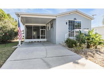 Gray mobile home with covered porch, landscaped yard, and spacious driveway at 3836 Chris Dr, Wesley Chapel, FL 33543