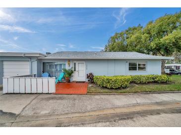 Charming single-story home featuring a tidy front yard, patio with colorful seating, and an attached garage at 1606 Berwick Ct # 10B, Palm Harbor, FL 34684