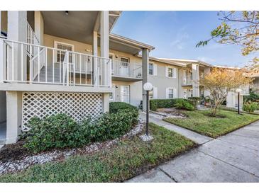 Exterior view of condo building with landscaped grounds at 1435 Millstream Ln # 202, Dunedin, FL 34698