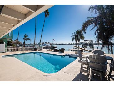 Outdoor pool, seating, and dock with boat lift offer waterfront living and stunning views at 807 Bay Point Dr, Madeira Beach, FL 33708