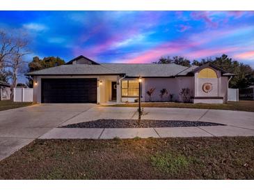 Updated one-story home with a dark gray garage door and landscaped yard at 9143 Bay Dr, Spring Hill, FL 34606