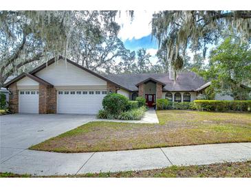 Brick house with three-car garage, mature landscaping, and a large front yard at 807 Belle Timbre Ave, Brandon, FL 33511