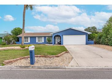 Blue house with white trim, a two-car garage, and a well-manicured lawn at 911 Silver Palm Way, Apollo Beach, FL 33572