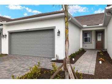 Front exterior view of a single-Gathering home with gray garage door and brick pathway at 12318 Hearts Ease St, Venice, FL 34293