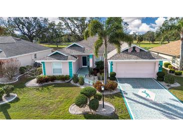 Charming one-story home featuring a 2-car garage, inviting facade, and lush landscaping at 324 Caloosa Palms Ct, Sun City Center, FL 33573