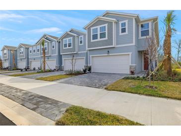 Row of charming townhouses with attached garages and paved driveways at 31472 Woodland Race Loop, Wesley Chapel, FL 33545