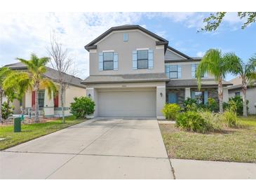 Two-story house with gray siding, light blue shutters, and a stone facade at 14319 Italia Dr, Wimauma, FL 33598
