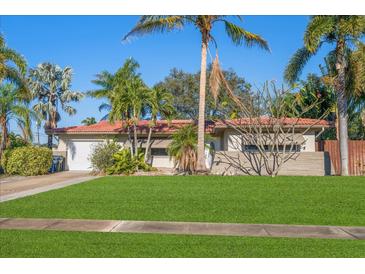 Single story home with red tile roof, lush landscaping, and a large grassy yard at 587 Hillcrest Dr, Largo, FL 33771