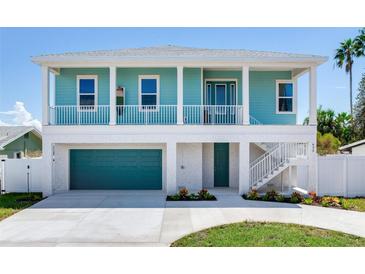 Two-story teal home with white trim, attached garage, and a walkway at 635 115Th Ave, Treasure Island, FL 33706