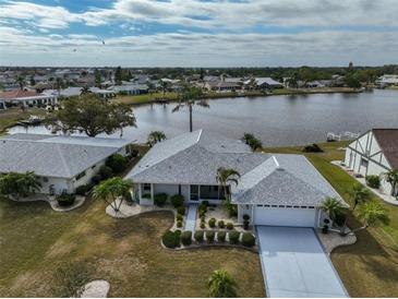 An aerial view of a home, featuring a well-manicured lawn, lakeside access, and neighborhood at 407 Blackhawk Cir, Sun City Center, FL 33573