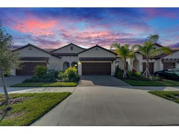 Two-story home with brown garage door and landscaping at 17554 Holly Well Ave, Wimauma, FL 33598