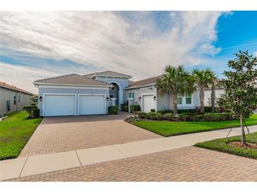 Two-story house with gray exterior, two-car garage, and landscaped front yard at 4919 Pamplona Ct., Wimauma, FL 33598