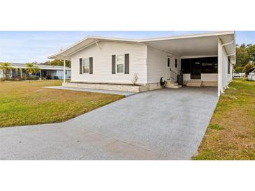 White single-wide manufactured home with carport and landscaped lawn at 36925 Kiowa Ave, Zephyrhills, FL 33542