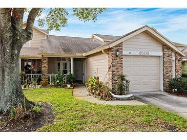 Tan two-story house with brick accents, attached garage, and landscaping at 6506 Remus Dr, New Port Richey, FL 34653