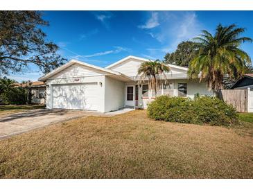 Single story house with attached garage, landscaping, and palm trees at 7837 Tiburon Dr, Largo, FL 33773