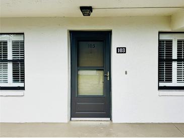 Exterior view of condo with dark door, white walls, and window shutters at 4910 Bay Ne St # 103, St Petersburg, FL 33703