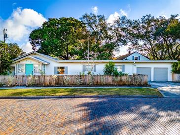 White single story home with teal door, gray garage, and brick driveway at 415 21St N St, St Petersburg, FL 33713