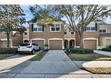 Tan three-story townhouse with two-car garage and landscaping at 4950 Pond Ridge Dr, Riverview, FL 33578