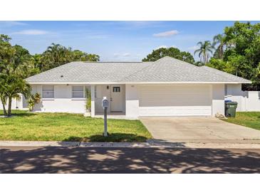 White single-story house with gray roof, two-car garage, and well-manicured lawn at 701 25Th Sw St, Largo, FL 33770