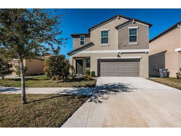 Two-story house with gray siding, two-car garage, and a well-manicured lawn at 7014 King Creek Dr, Sun City Center, FL 33573