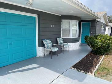 Gray house with teal garage door, landscaping, and driveway at 3148 Harvardston Loop, Holiday, FL 34691