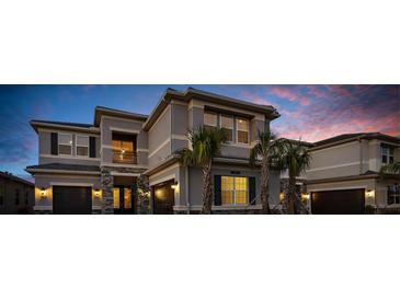 Luxury two-story house with stone accents and illuminated windows at dusk at 32317 Rosewood Meadow Ln, Wesley Chapel, FL 33543