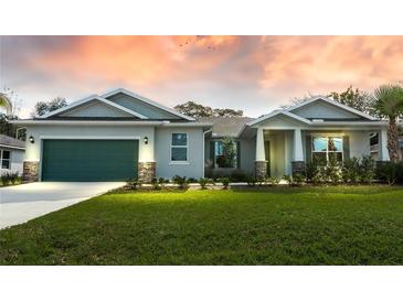 Craftsman style home with green garage door and stone accents at 15084 Mcgraw Ave, Port Charlotte, FL 33953