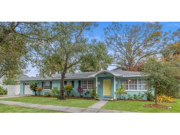 Charming light blue house with a yellow door, nicely landscaped lawn, and walkway at 1901 10Th N St, St Petersburg, FL 33704