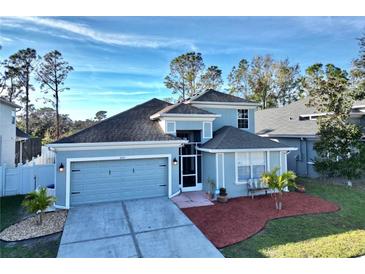 Two-story house with gray roof, blue exterior, and landscaped yard at 6047 Twin Bridges Dr, Zephyrhills, FL 33541