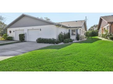 White brick home with gray accents, two-car garage, and lush lawn at 3340 Mcmath Dr, Palm Harbor, FL 34684